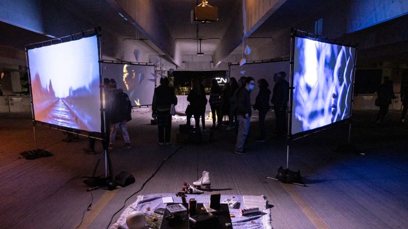 A group of people looking at four projection screens